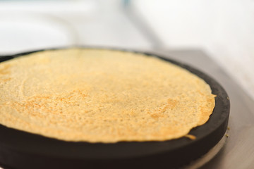 Cooking pancake on round griddle with copy space.