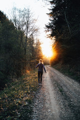 Young female running in the forest at sunset.