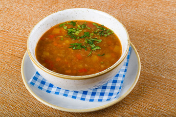 Fresh lentil soup in a white bowl, served in a restaurant setting, selective focus.