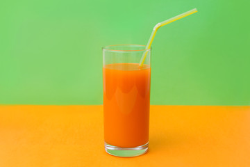 a glass of carrot juice on a green background