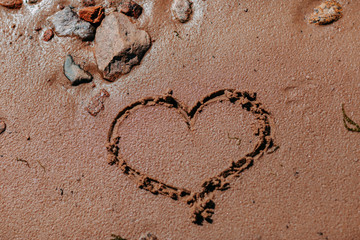 Ocean shore, sand and rocks on the sea coast. Heart drawing on sandy beach.