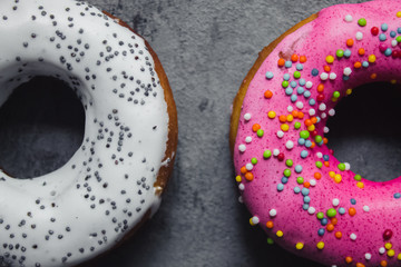 Homemade two doughnuts pink with rainbow sprinkles and white with poppy seeds in the center on the...