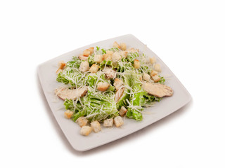 Salad of chicken breast, lettuce, croutons, and grated parmesan on a square plate