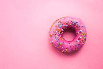 Homemade circle donut with pink icing and rainbow sprinkles on the trendy soft pink background...