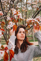 A girl with long hair walks in a blooming garden, spring blooming pink cherry trees, close-up portrait