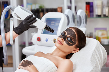close-up of cosmetologist arm working on female face with beauty laser machine