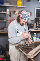 Male carpenter working on old wood in a retro vintage workshop.