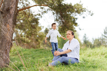 Fototapeta premium Stilish mother and handsome son having fun on the nature. Happy family concept. Beauty nature scene with family outdoor lifestyle. Happy family resting together. Happiness in family life. Mothers day.