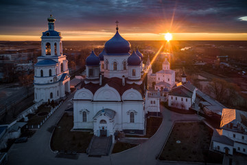 Fototapeta na wymiar Sun rising over the All-Saints Bell Tower and Our Lady of Bogolyubovo Church in the village of Bogolyubovo, Vladimir region, Russia