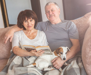 Happy elderly couple sitting on sofa at home
