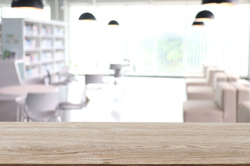 The empty wooden table surface for placing objects against a blurred white hallway background