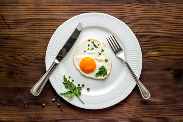 Fried eggs on plate - dark wooden table top view