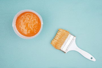 Paintbrush and bucket of ocher paint,top view.  Brush and paint on blue background