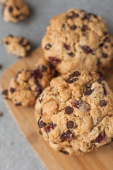 Fresh organic homemade cookies with chocolate chips and dried berries on wooden board on table
