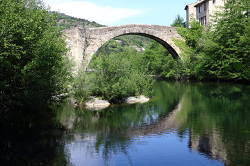 Fototapeta na wymiar Old stone bridge over the river in Le Vigan, France