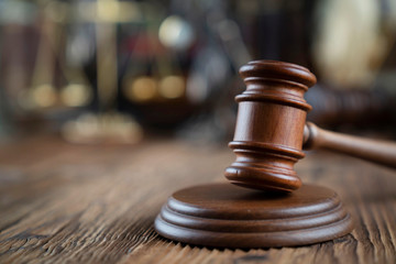 Lawyers office concept. Law symbols composition - gavel and Themis statue on rustic wooden desk.