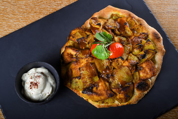 Baked chicken tights and breast served on a pita bread or focaccia pizza dough, restaurant setting