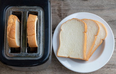 Toaster with bread on a plate on a wooden table