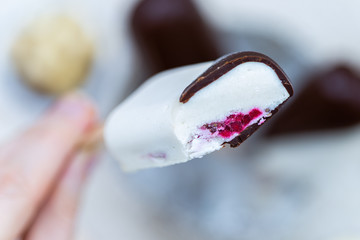Female hand holding a home made raw vegan ice cream with sliced top and blurred background.