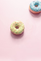 assorted donuts of different flavors as bubblegum, bilberry and strawberry with frosted and filled with fruit jam and cream, colored glazed and sprinkled donuts on pink background, pistachio