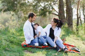 happy young family spending time outdoor on a summer day have fun at beautiful park in nature while sitting on the green grass. Happy family.