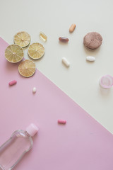 A close-up top view of various pills,macaroni  and lime on pink and yellow background. Medical, pharmacy and health care concept. Copy place for text or logo. Dietary supplements and vitamins.