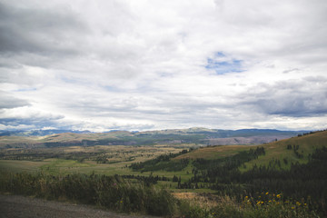 Hills view with clouds and green fields in Yellowstone National Park United States with wallpaper...