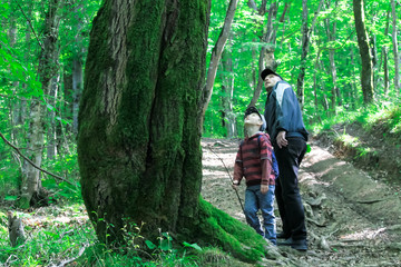 Family with children hiking in the forest. Tourists travel through the woods.
Scout kids and dad explore the beautiful forest. Adventure Time.