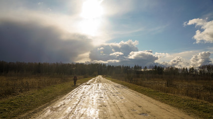 Cloudy sky after heavy rain and a country road shining under the sun