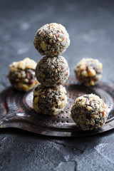 Healthy raw vegan sweets. Homemade energy balls with hazelnuts and wood slabs on dark oak board on black background