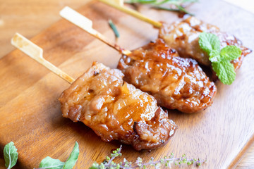 Grilled skewered milk pork on wooden background - Local Thai street food style