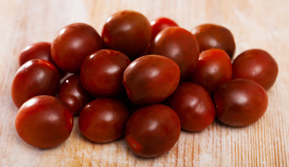 Closeup of fresh ripe kumato tomatoes on wooden surface. Organic vegetables concept