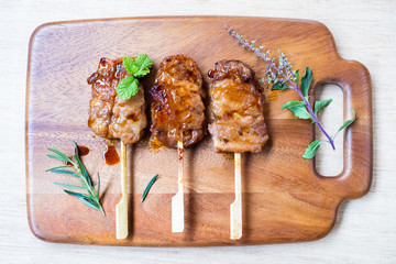 Grilled skewered milk pork on wooden background - Local Thai street food style