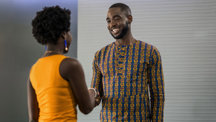 Two smiling young African businesspeople shaking hands in an off