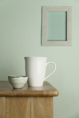 white ceramic mug and tea cup on nature wood table with vintage blue cement and grey picture frame wall for food drink and interior background