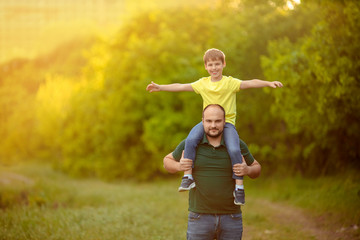 Father's day. Happy family dad and son play outdoors, a man holds a child on his shoulders