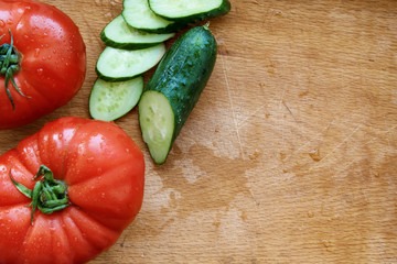 Tomatoes and cucumber on a wooden cutting board. Scratch