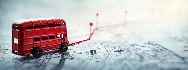 Red bus, pins and route laid on a map of the city. Concept on the  adventure, discovery,...