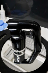 isolated airbrush pistol with plastic cup of paint  for instant tanning, tan spray body paint on white table in professional beauty salon