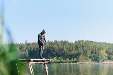 Fishing in river.A fisherman with a fishing rod on the river bank. Man fisherman catches a fish pike.Fishing, spinning reel, fish, Breg rivers. - The concept of a rural getaway. Article about fishing.