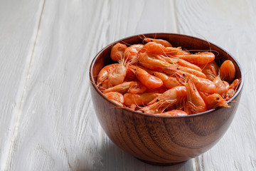 Fresh cooked sea shrimps in a bowl on a white wooden background. Seafoood. Sea products macro. Black sea shrimp.