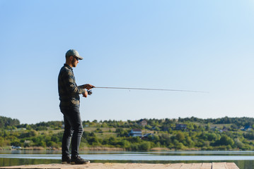 A man catches a fish on a spinning fishing in the summer