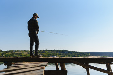 A man catches a fish on a spinning fishing in the summer