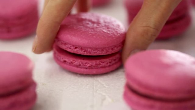 Close-up view of many rows of pink macarons macaroon on white background. Classical French dessert. The hand takes away one