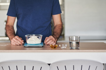 headless portrait of a man weighing flour on a digital scale to prepare a dough