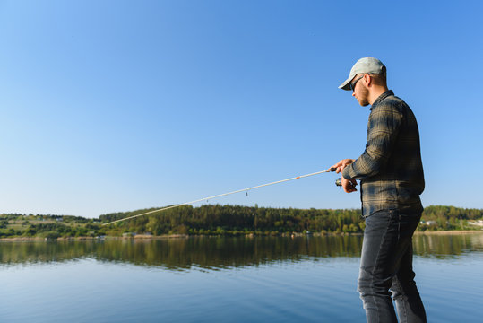 A man catches a fish on a spinning fishing in the summer