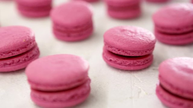 Close-up view of many rows of pink macarons macaroon on white background. Classical French dessert.