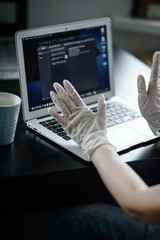 a woman works at home in a mask and gloves on a computer, remote work