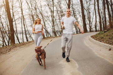 Obraz premium Beautiful couple in a park. Sportsman in a sportswear. Couple with a dog