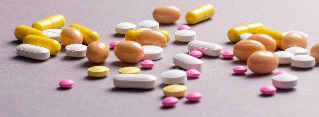 Pile of various colorful pills isolated on gray